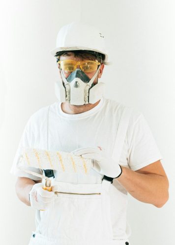 A professional painter wearing safety gear holding a paint roller, ready for work.